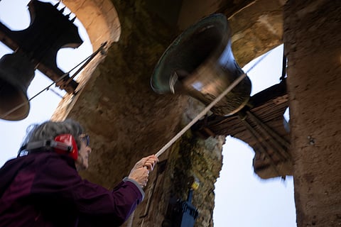 Roser Reixach, a student of the Vall d'en Bas School of Bell Ringers, performs playing a bronze bell at the church bell tower
