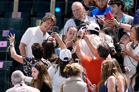 Actor Tom Cruise (left) poses for pictures with fans as he attends the women's artistic gymnastics qualification round at the 2024 Summer Olympics in Paris, France on Sunday (July 28)