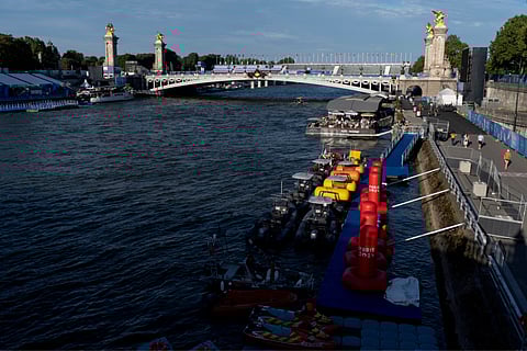 Watercraft and buoys sit along the Seine river as the triathlon event venue on the Pont Alexandre III bridge stands in the background at the 2024 Summer Olympics on Sunday (July 28) in Paris.