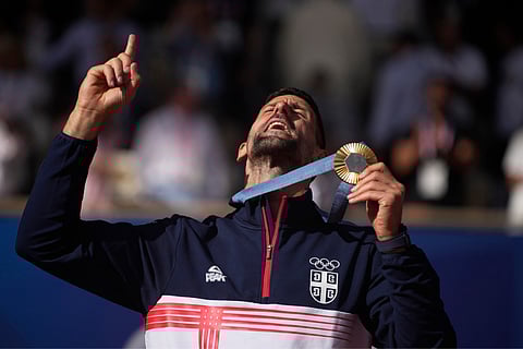 Serbia's Novak Djokovic shows his gold medal after defeating Spain's Carlos Alcaraz in the men's singles tennis final at the Roland Garros stadium during the 2024 Summer Olympics on Sunday, Aug. 4