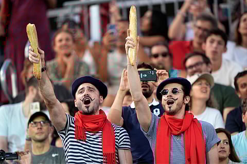 Thomas Zellner (left) and Thibault Vinson celebrate being Parisian while cheering for France's Lezana Placette and Alexia Richard in a beach volleyball match against Germany at the 2024 Summer Olympics (July 29)