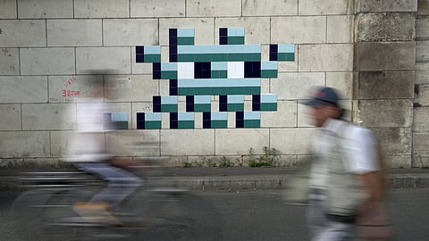 A cyclist rides in front of an Olympic-themed new mosaic by the mysterious French street artist known only by the name Invader