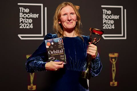 Samantha Harvey poses with the trophy and her book "Orbital" after winning the Booker Prize award 2024, in London, Tuesday, Nov. 12, 2024