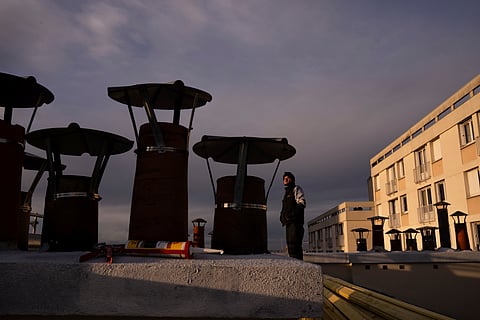 A roofer watches the sunset from the roof of a building in Paris