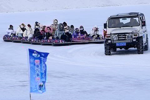 Visitors enjoy a ride on a tube slide pulled by a vehicle on the frozen Songhua river in Harbin, China's Heilongjiang province on Thursday, Jan. 9, 2025