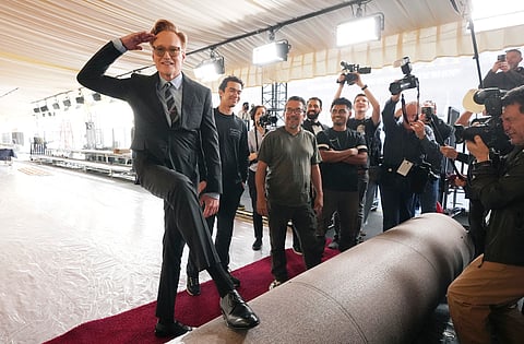 Conan O'Brien (left) host of Sunday's 97th Academy Awards, salutes photographers before helping to roll out the red carpet at the Dolby Theatre on Wednesday, Feb. 26, 2025, in Los Angeles