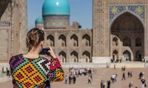 A tourist outside Tillya-Kari madrasah in Uzbekistan's Samarkand