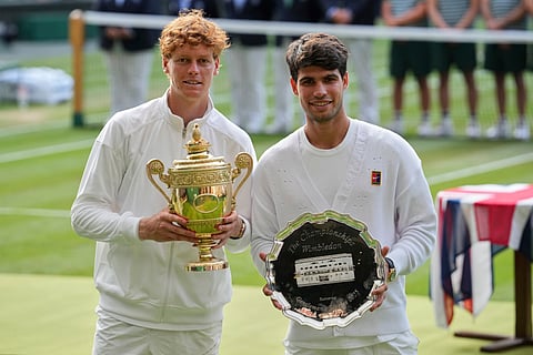 Italy's Jannik Sinner, left, celebrates with the trophy after beating Carlos Alcaraz of Spain, right, to win the men's singles final