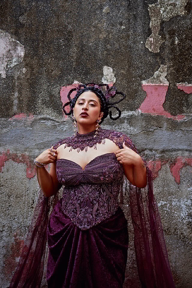 Raja Kumari wearing a wine velvet corset gown with sheer overlay