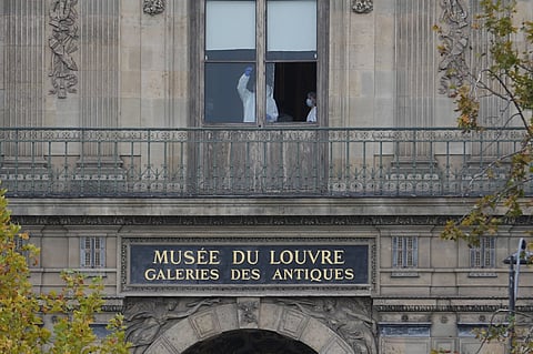 Police officers work inside the Louvre museum in Paris on Sunday