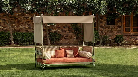 Sculptural outdoor daybed with weather-proof cushions and a removable canopy for shade.