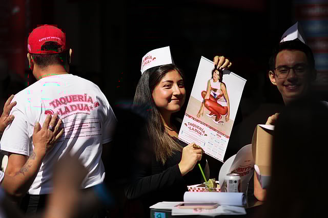 A consumer holds up a Dua Lipa calendar during the opening of the music star's taqueria, a pop-up restaurant for her fans in Mexico City