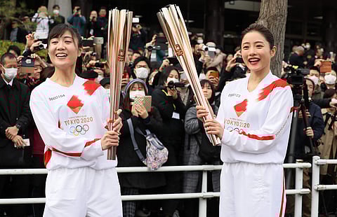 A torchbearer and Satomi Ishihara with the Olympic torch (AFP / JIJI PRESS / STR)