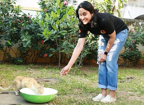Actor Regina Cassandra offering a thirsty kitten a drink of water