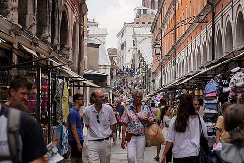 In frame: Tourists walk in a crowded street in Venice, Italy
