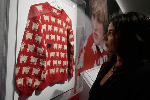 A employee looks at the historic Princess Diana black sheep jumper at the auction house Sotheby's in London