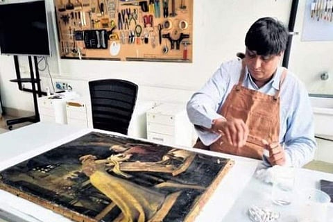 Achal Pandya restores an oil on canvas work (artist unknown) at the IGNCA Conservation Lab