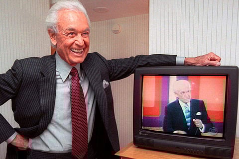 Bob Barker leans on his hotel room television showing his image, during an interview in 2000