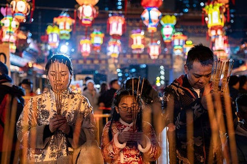 In frame: Worshippers pray as they burn their first joss sticks at a temple to welcome in the Lunar New Year of the Dragon in Hong Kong