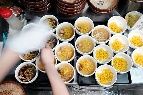 In frame: A staff member prepares small bowls of noodle for participants of Tokyo Ramen Tours 