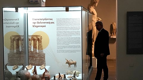 A presidential security officer stands behind antiquities repatriated from Germany and put on display at the Archeological museum, in capital Nicosia