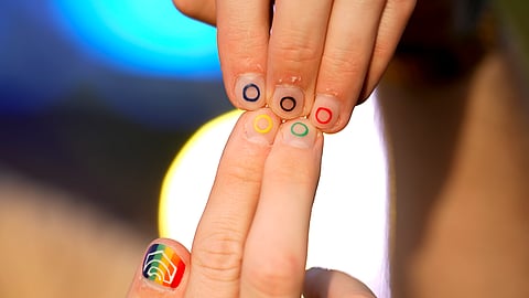Jeremy Goupille shows his nails painted with the rainbow colors and the Olympic rings at the opening of Pride House