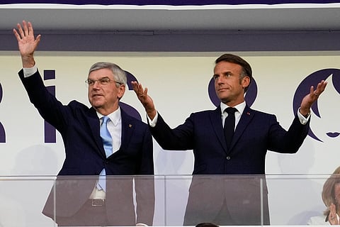 IOC President Thomas Bach and French President Emmanuel Macron wave during the 2024 Summer Olympics closing ceremony at the Stade de France, Aug. 11, 2024, in Saint-Denis, France