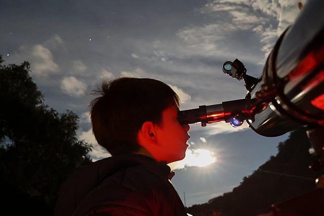 A youth looks through a telescope during a stargazing and comet-watching gathering at Joya-La Barreta Ecological Park