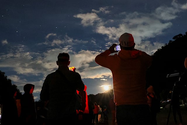 People take photos of the sky at a stargazing and comet-watching gathering at Joya-La Barreta Ecological Park in Queretaro