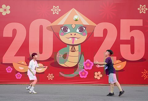 Two boys play football in front of a billboard welcoming the New Year 2025 in Ho Chi Minh city, Vietnam on Tuesday, Dec.31, 2024.