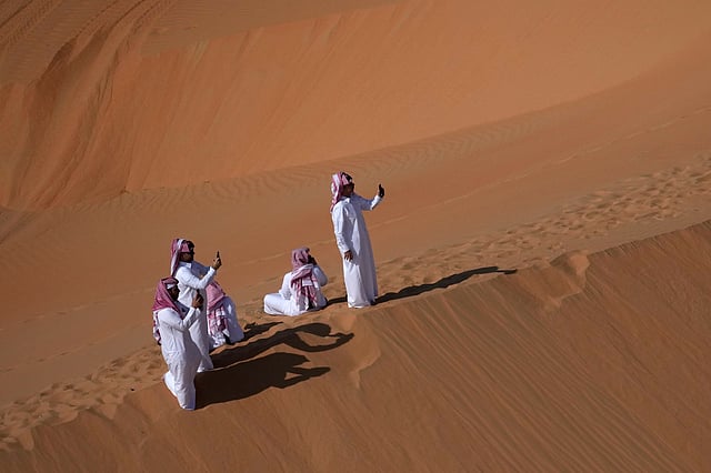 People take photos of drivers during the tenth stage of the Dakar Rally between Haradh and Shubaytah, Saudi Arabia, Wednesday, Jan. 15, 2025.