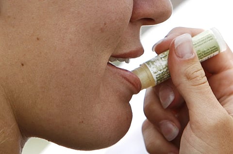 A woman applies lip balm