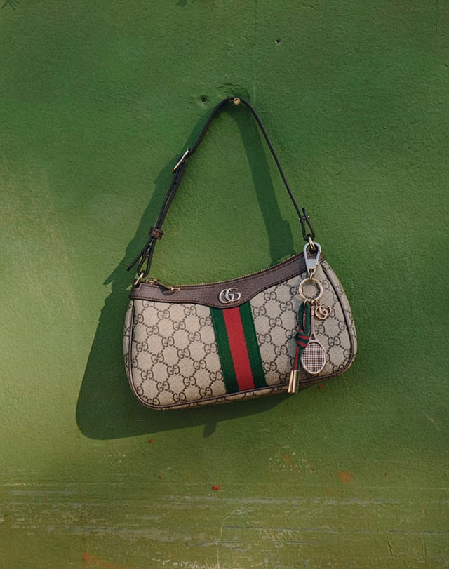 Designer handbag adorned with playful tennis-themed charms, blending sporty elegance with fashionable detailing.