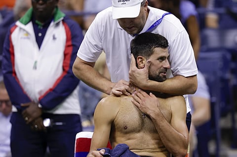 Novak Djokovic works with a trainer during the US Open
