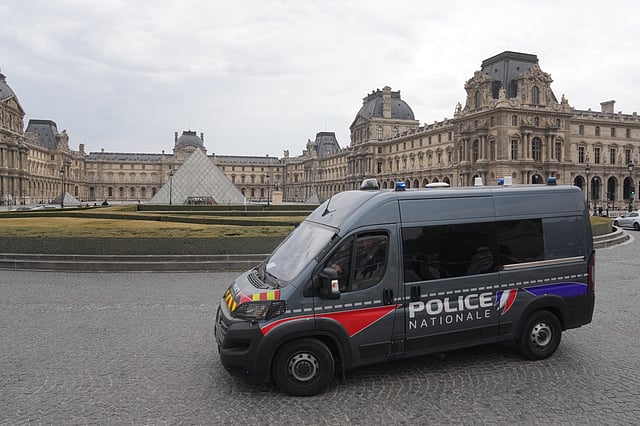 A police van patrols in the courtyard of the closed Louvre museum after a robbery