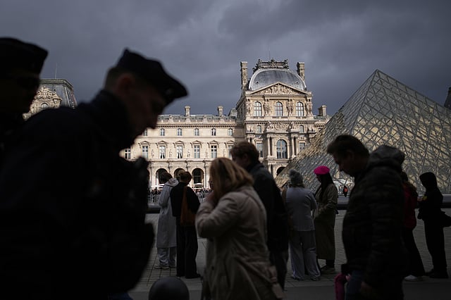 Police officers, left, patrol as people queue to enter Le Louvre museum Monday