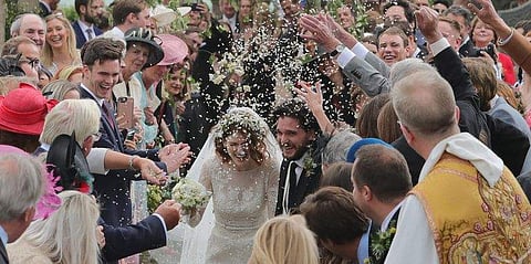 Kit Harington and Rose Leslie walk through guests as they are showered upon with flowers