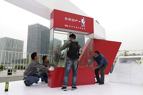 Workers dismantle signage for an NBA fan event in Shanghai, China (AP Photo)