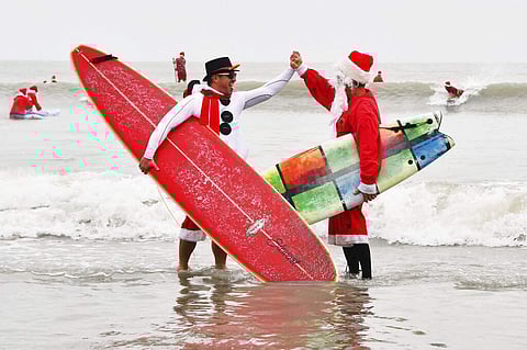 Surfing Santas (Malcolm Denemark/Florida Today via AP)