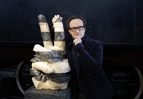 Designer Lucio Micheletti with his creation, Victory, made with maple wood and recycled plastic from bottles and containers, at the RO Plastic - Master's Pieces exhibition. (AP Photo/Luca Bruno)