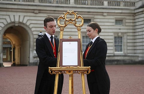 Footmen Stephen Kelly and Sarah Thompson bring out the easel in the forecourt of Buckingham Palace to formally announce the birth of a baby boy to Prince Harry and Meghan. (Yui Mok/Pool Photo via AP)