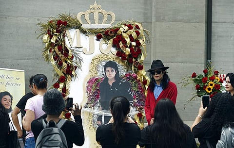 Michael Jackson impersonator Rem Garza of Long Beach, Calif., poses next to a shrine to the late pop star outside his final resting place in Holly Terrace at Forest Lawn Cemetery