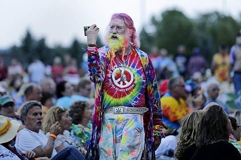A man walks through the crowd during an Arlo Guthrie concert at a Woodstock 50th anniversary event in Bethel, NY, Thursday, Aug 15, 2019. (AP Photo/Seth Wenig)