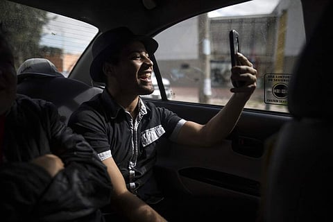 Venezuelan migrant Alexander Beja speaks with his fans on his smart phone, as he rides in a taxi in Bogota, Colombia. (AP Photo/Ivan Valencia)
