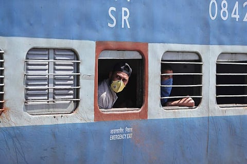 Passengers wearing masks look out from a train in Jammu. India's colossal railway system has come to a halt as officials take measures to keep the coronavirus from spreading. (AP Photo/Channi Anand)