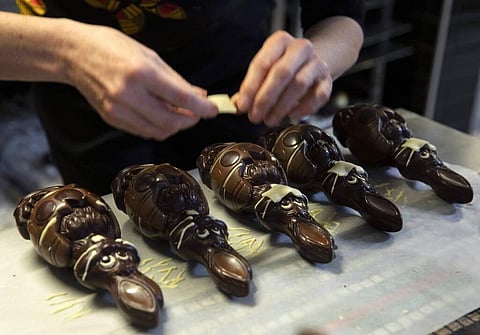 Genevieve Trepant makes masks for chocolate rabbits at Cocoatree, in Lonzee, Belgium. Many shops have resorted to online sales, delivery or pick up on site during lockdown. (AP Photo/Virginia Mayo)