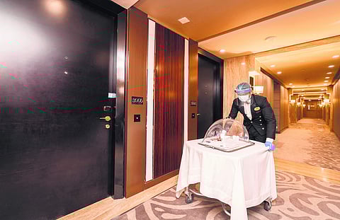 A server clad in mask and visor on room service rounds at ITC Grand Chola
