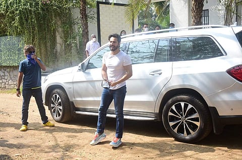Varun Dhawan wore a white T-shirt and blue jeans along with a mask as he stepped out of the car and made his way into the venue, briefly stopping to pose for the press cameras