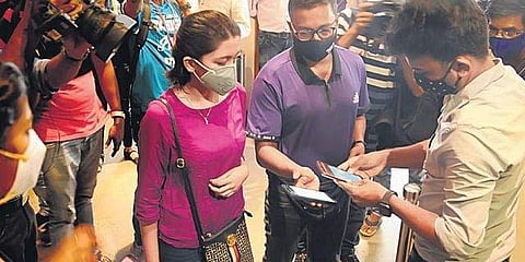 A theatre employee scans QR code on customer’s phone for contactless ticketing