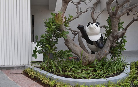 A life-size panda waves hello by the outdoor seating section